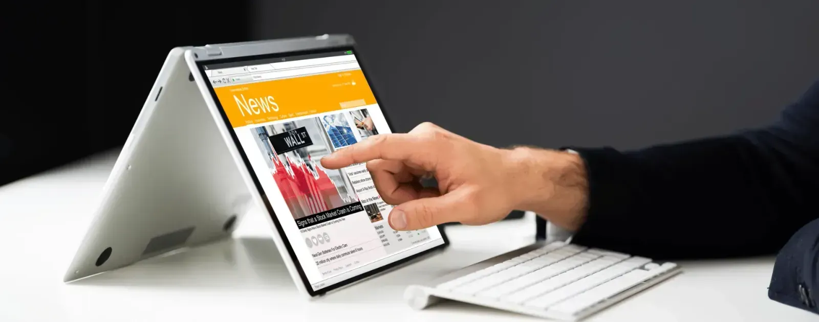 A businessperson is scrolling through a tablet, looking for news on mergers and acquisitions.