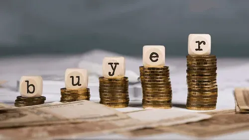 Wooden dice with the word 'buyer' on top of coins that are trending upward, placed on a surface resembling currency. This symbolizes a successful business sale.