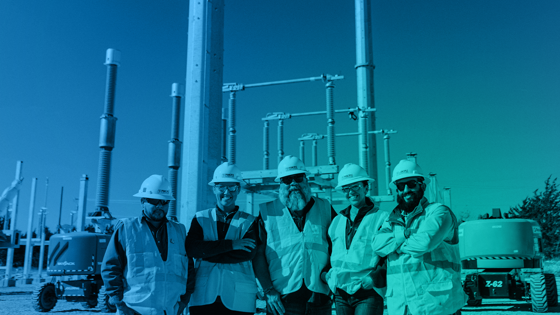Five construction workers wearing hard hats and reflective safety vests standing in front of electrical infrastructure.