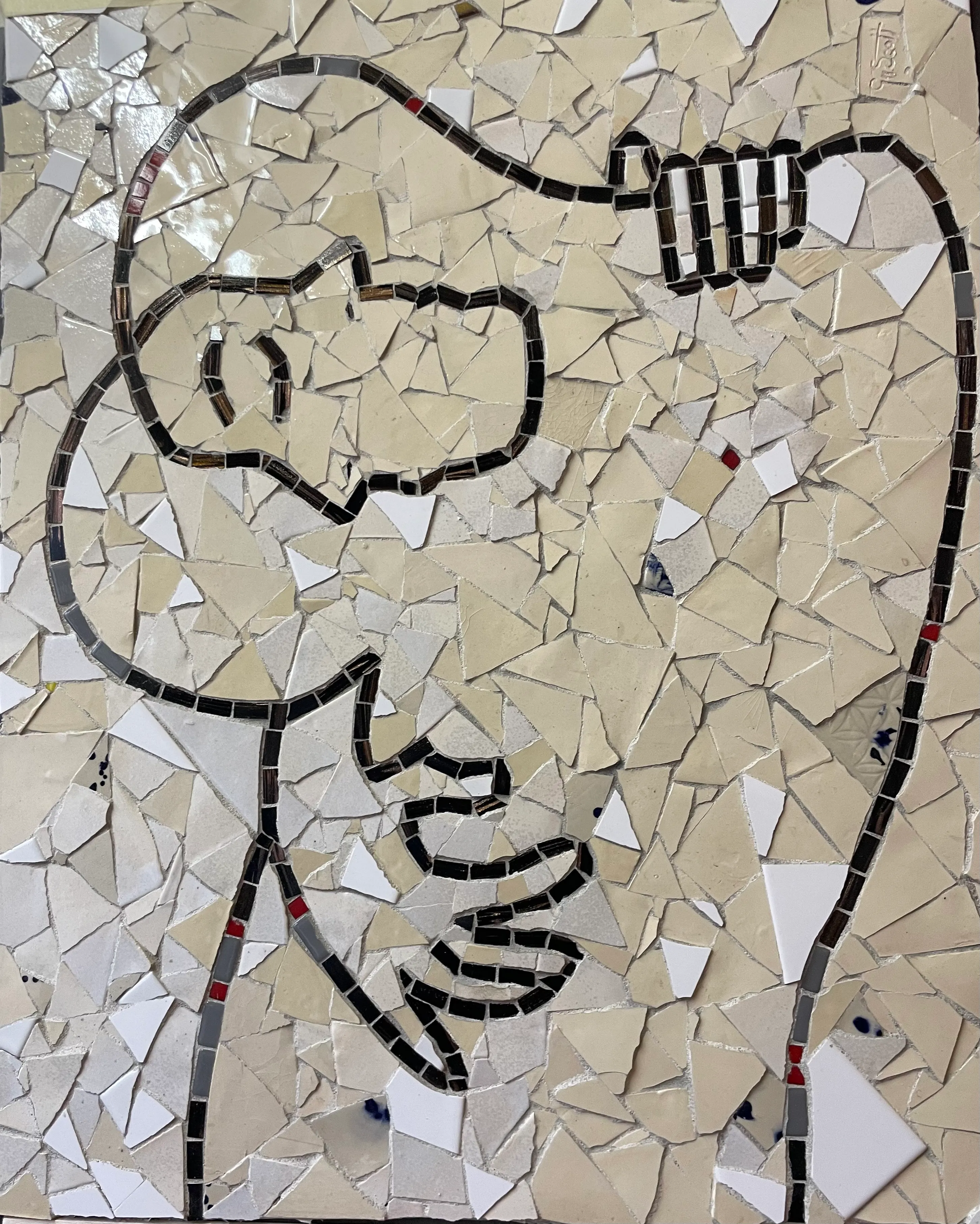 Mosaic artwork depicting a stylized face with hands in front, outlined in black tiles on a beige and white tiled background.