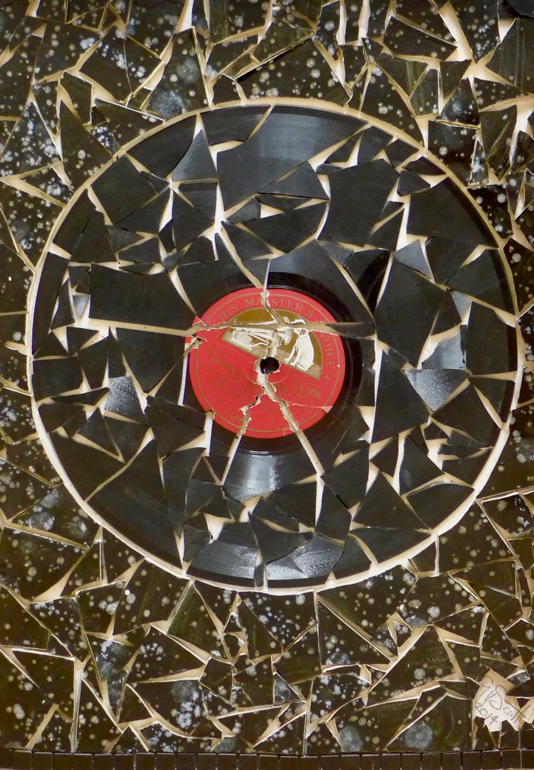 Mosaic artwork composed of broken vinyl record pieces arranged around the red label at the center.