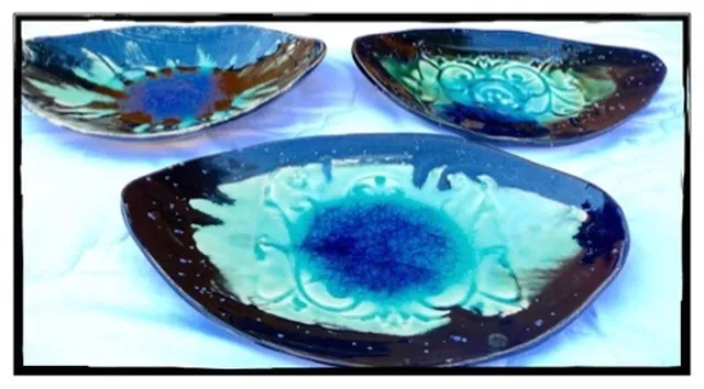 Three ceramic decorative plates with blue and turquoise glaze arranged on a white surface.