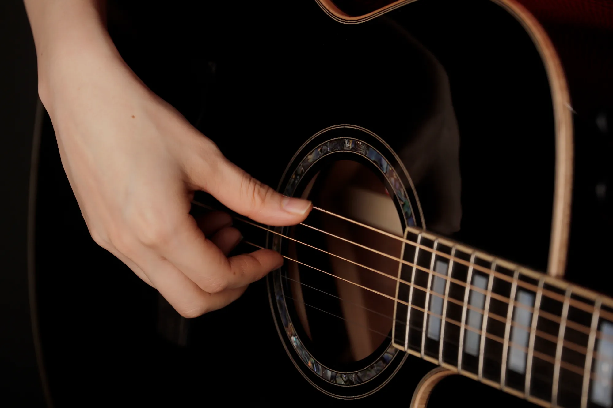 Close-up of a guitarist's hands playing an acoustic guitar.