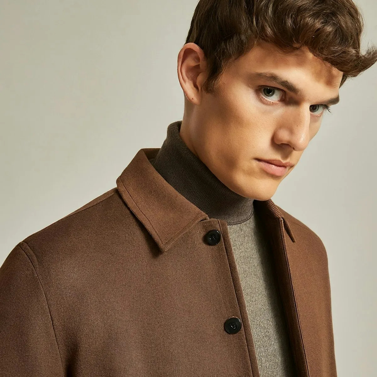 A man in a brown coat looking at the camera.