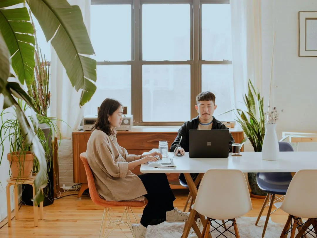 A man and woman sitting at a table with a laptop.