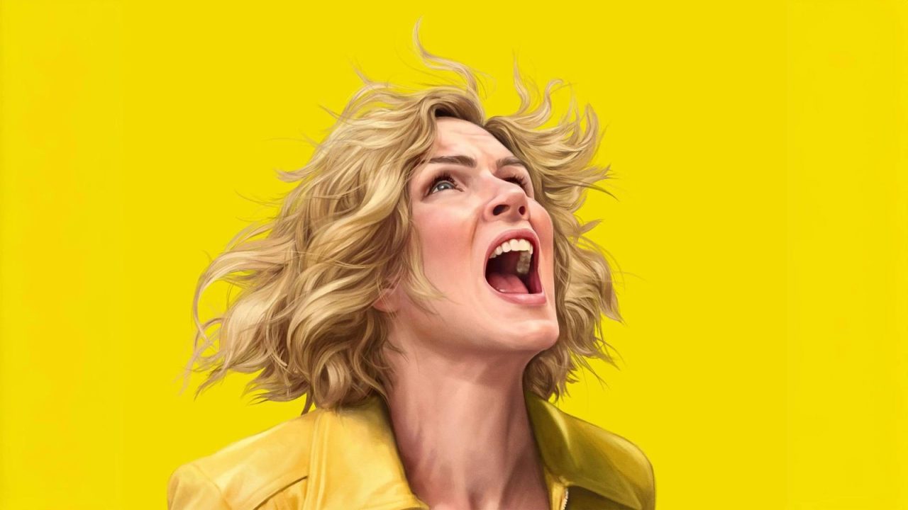 Blonde woman with curly hair wearing a yellow jacket shouting or screaming against a bright yellow background.