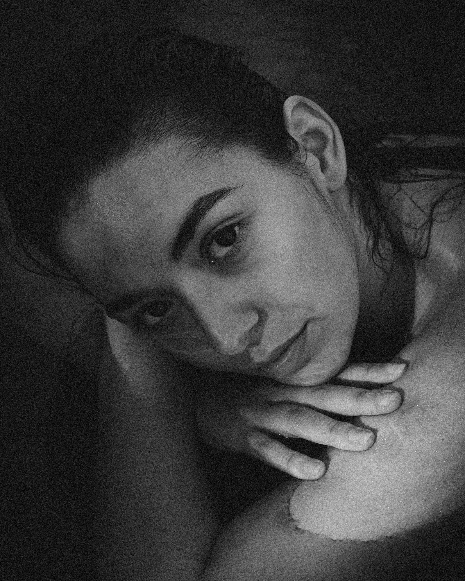 Close-up black and white portrait of a woman resting her head on her arm with a calm expression.