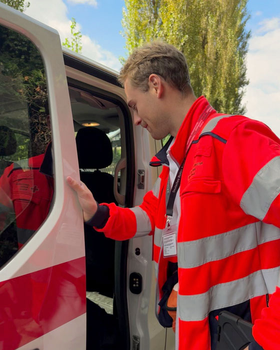 Ein Fundraiser in Ausrüstung des DRK öffnet die Tür des Einsatzwagens und steigt hinein.