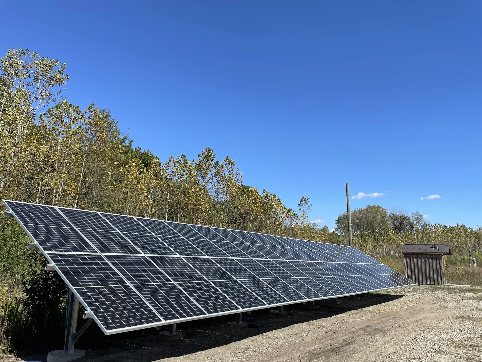 Aisle between large gray server racks with overhead fluorescent lights in a data center.