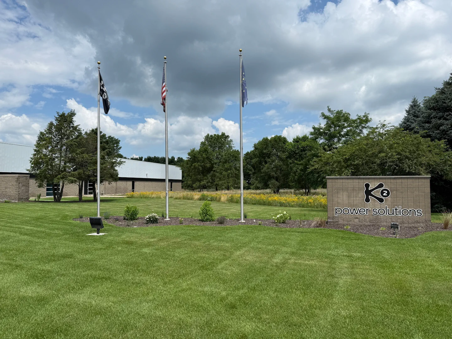 Aisle between large gray server racks with overhead fluorescent lights in a data center.