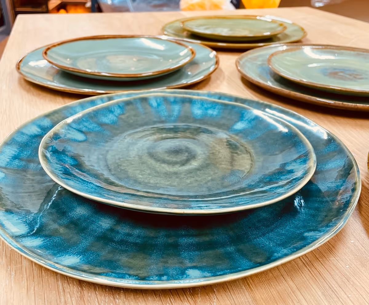 Stacked ceramic plates with blue and green glaze patterns on a wooden table.