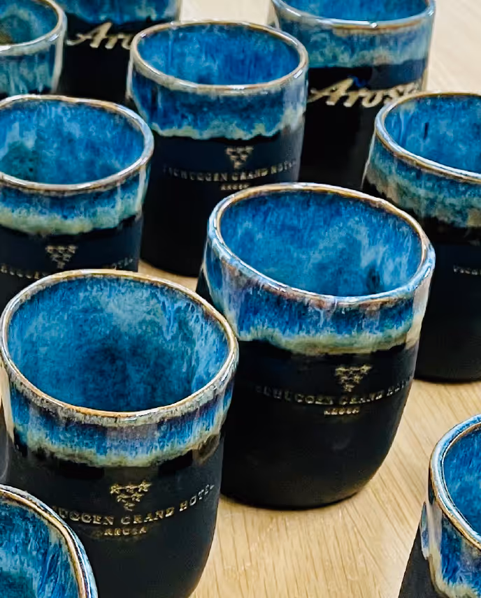 Close-up of ceramic cups with a blue and black glaze, arranged on a wooden surface.