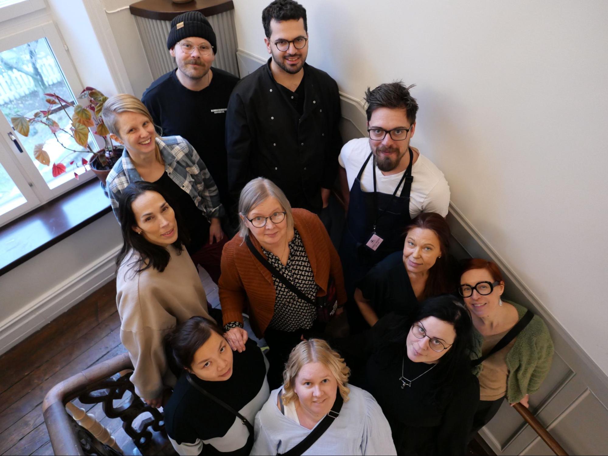 Grupp av tio personer som står i en trappa och ser upp mot kameran.