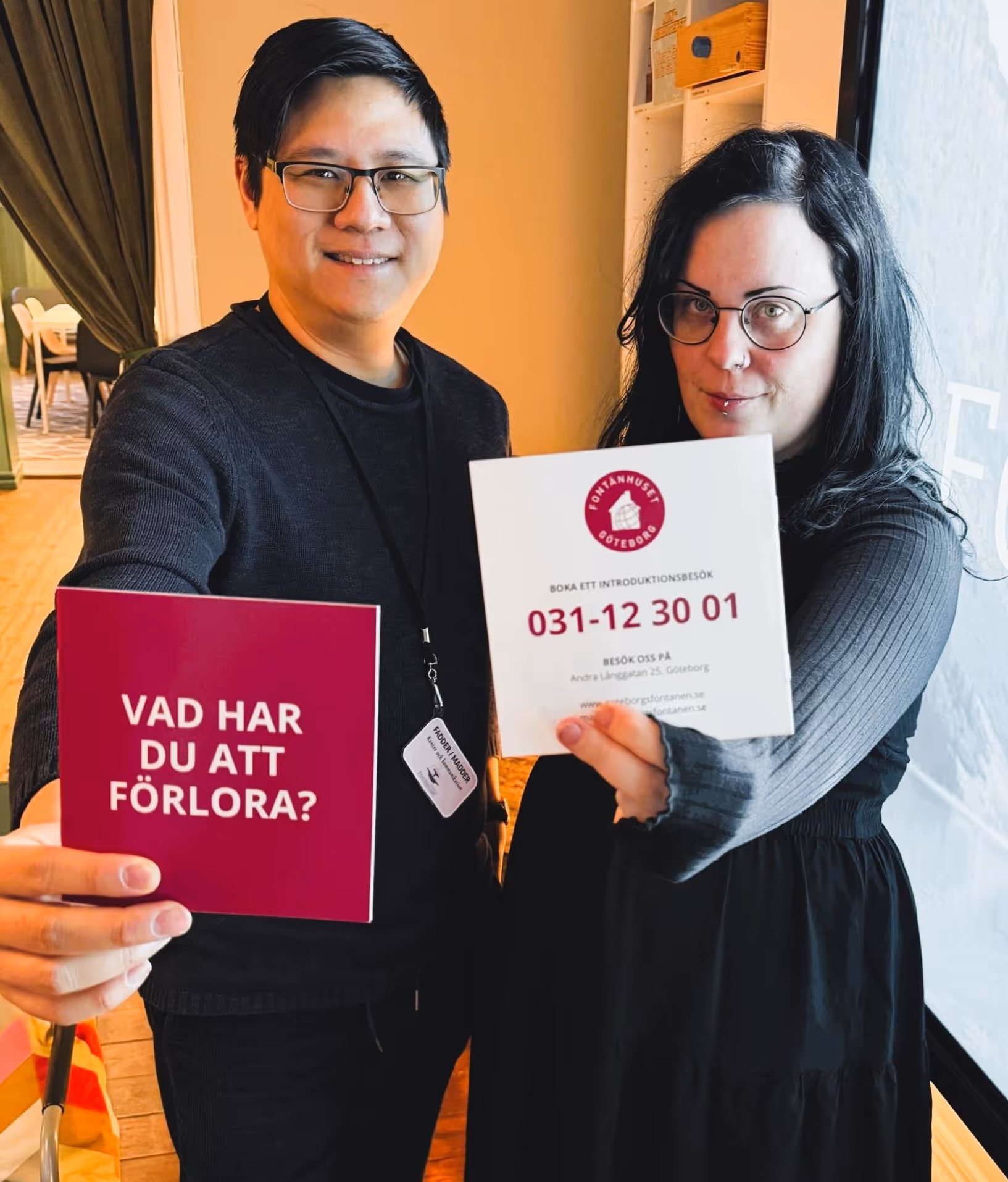 Två personer håller fram kort, ett rött med texten 'Vad har du att förlora?' och ett vitt med kontaktinformation för Fontanhuset Göteborg.