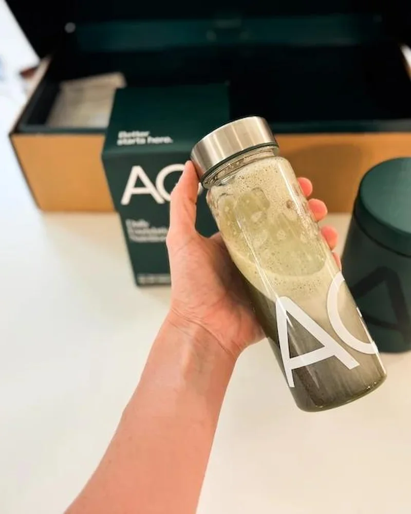 AG1 bottle being shaken beside its starter kit