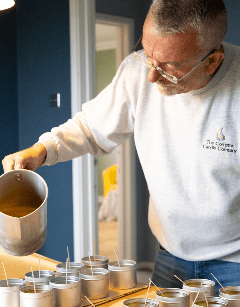 A candle maker at The Compton Candle Company pouring wax into tins.