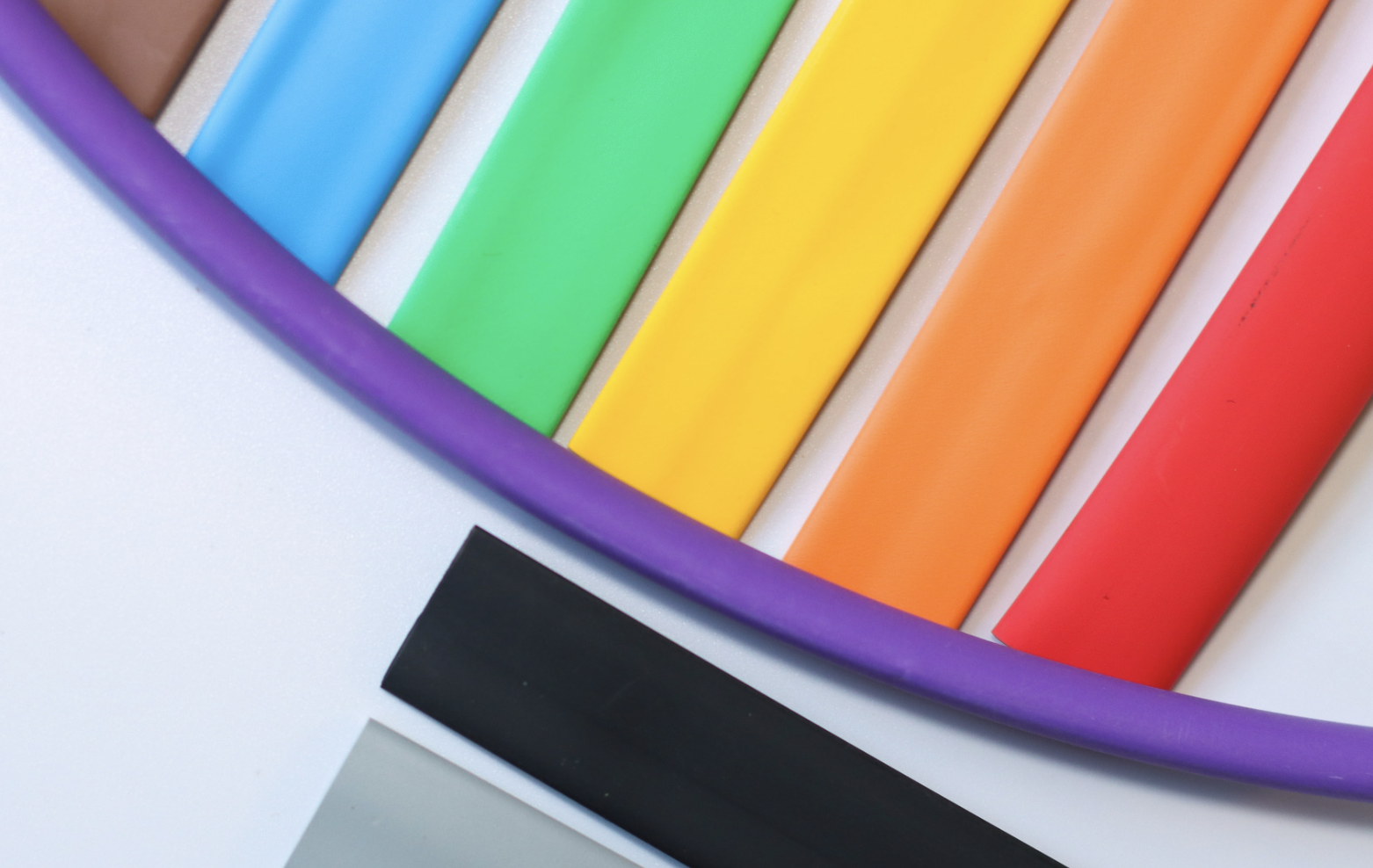 Close-up of colored insulation tubes arranged on a white surface, including purple, blue, green, yellow, orange, red, black, and grey tubes.