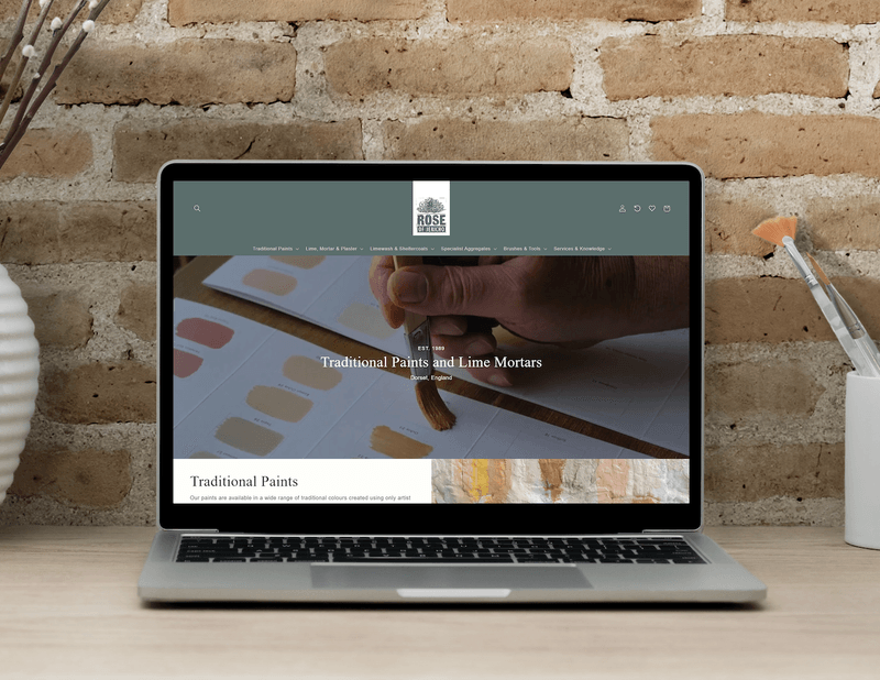 Rose of Jericho website displayed on a laptop against a stone wall.