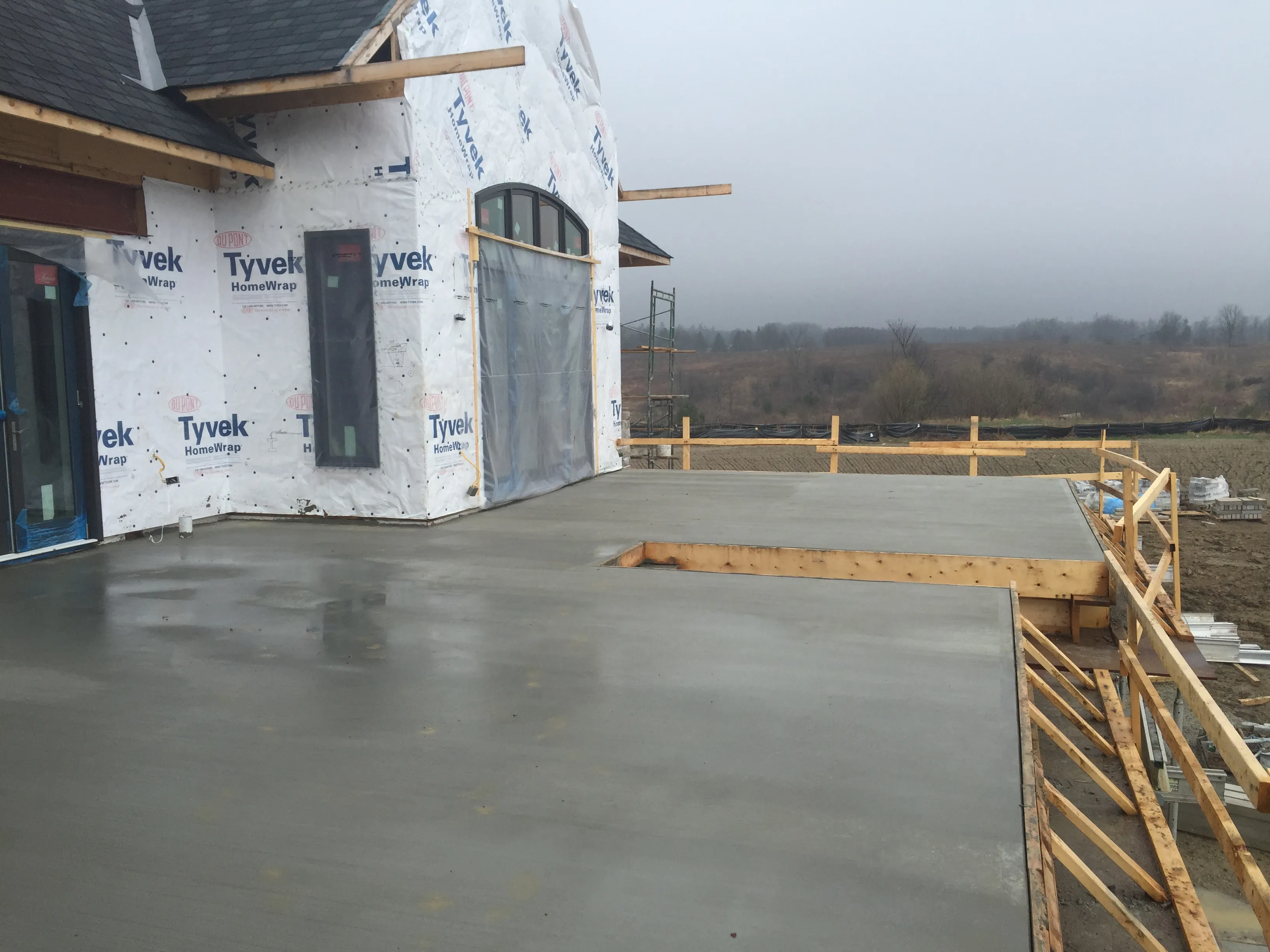 Wet concrete porch slab poured next to a new home under construction