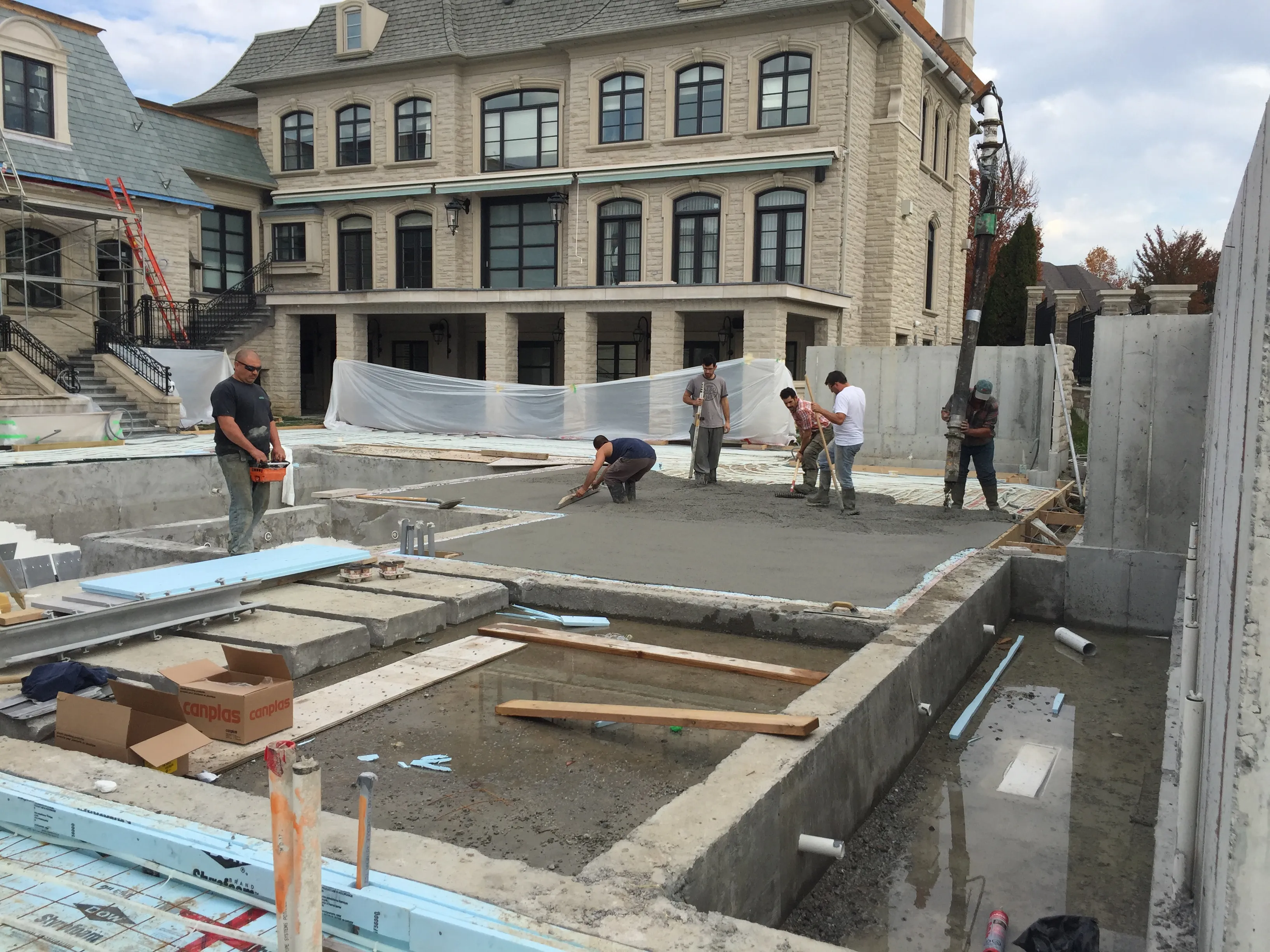 Concrete crew finishing a slab pour at a stone luxury home