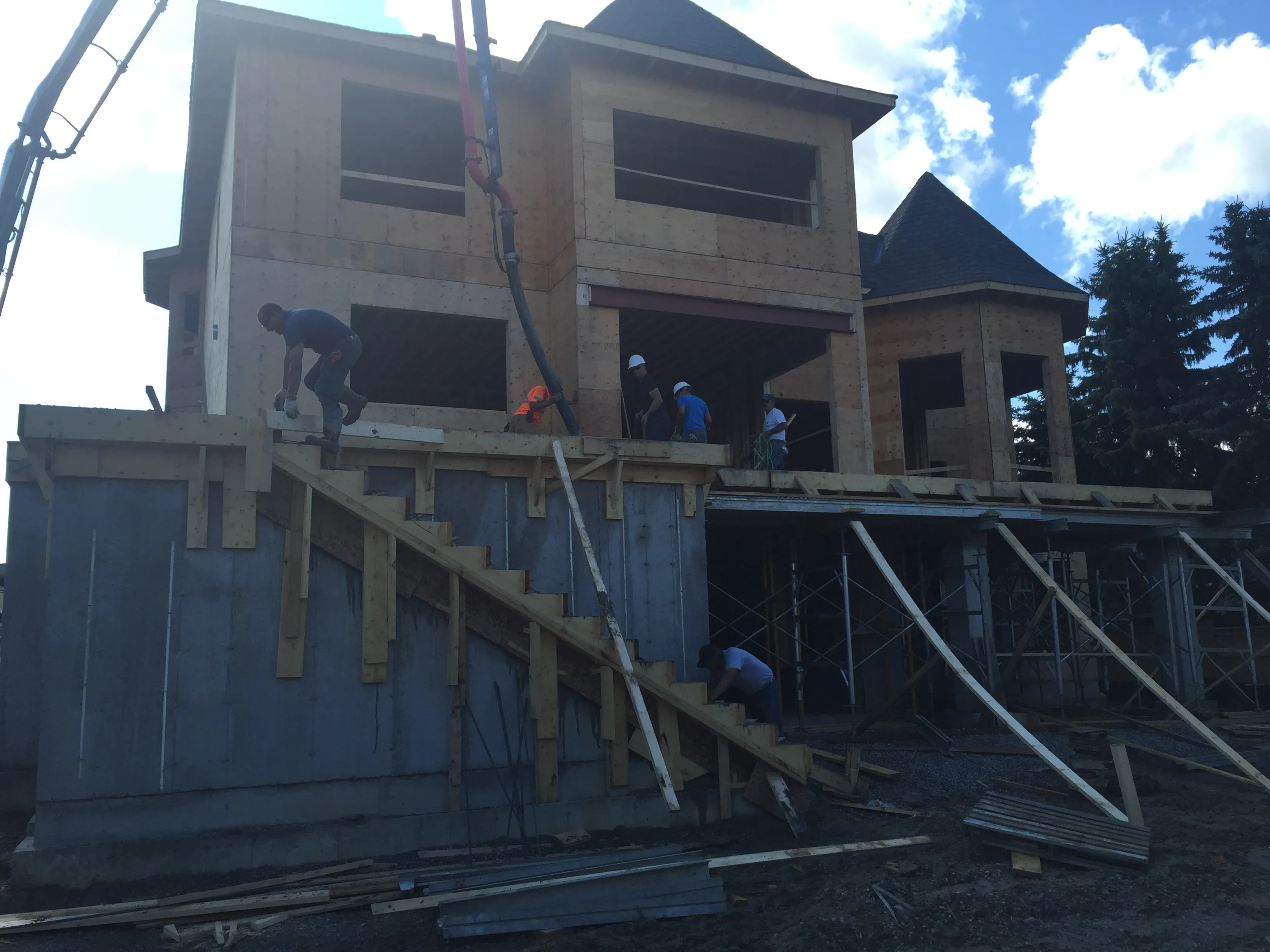 Crew pumping concrete for elevated porch stairs on a new home