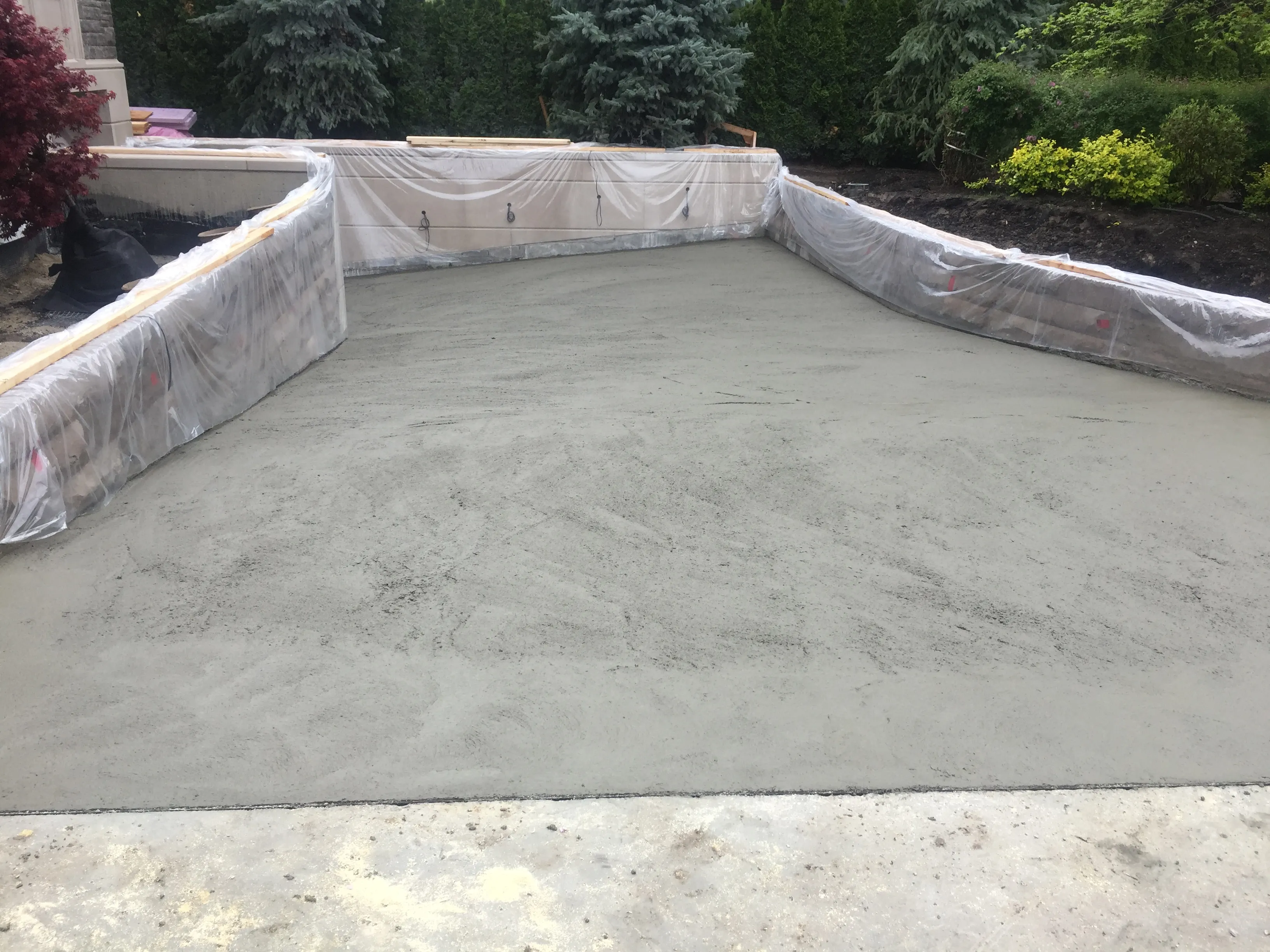 Freshly poured concrete patio slab with protected stone walls
