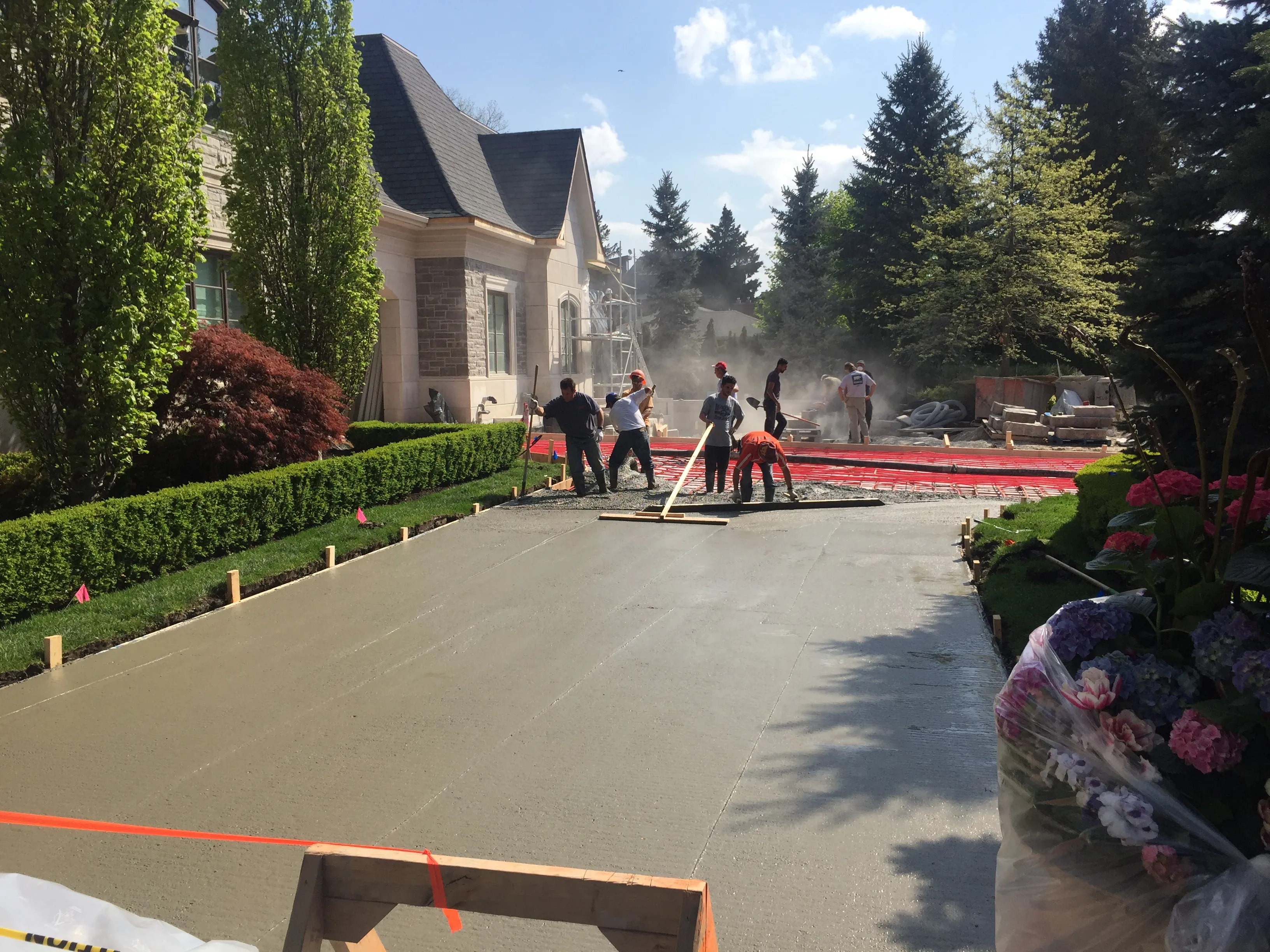 Crew placing and screeding a new concrete driveway at a custom home