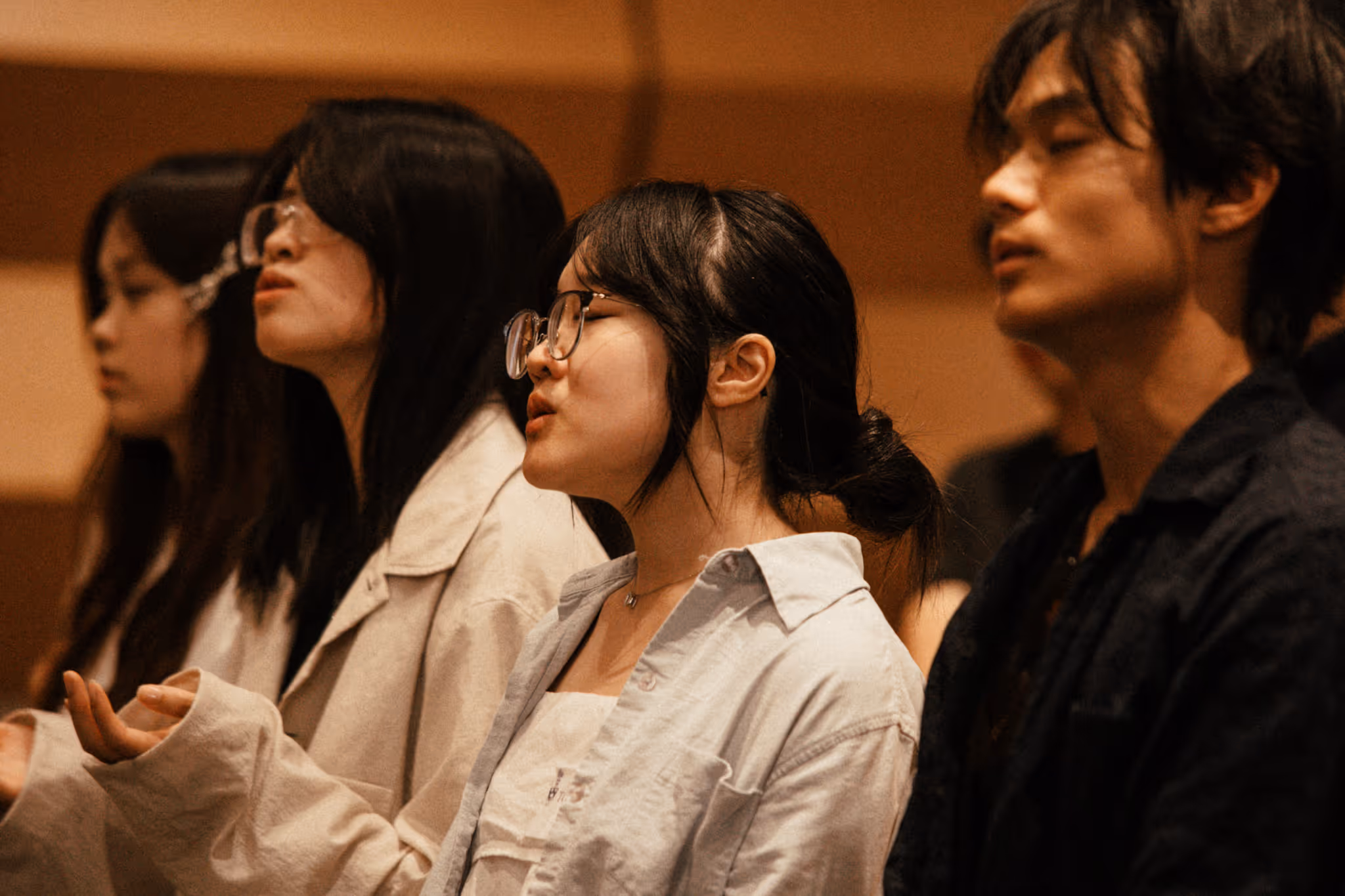 Young people with eyes closed in worship during an AFC conference or ministry event