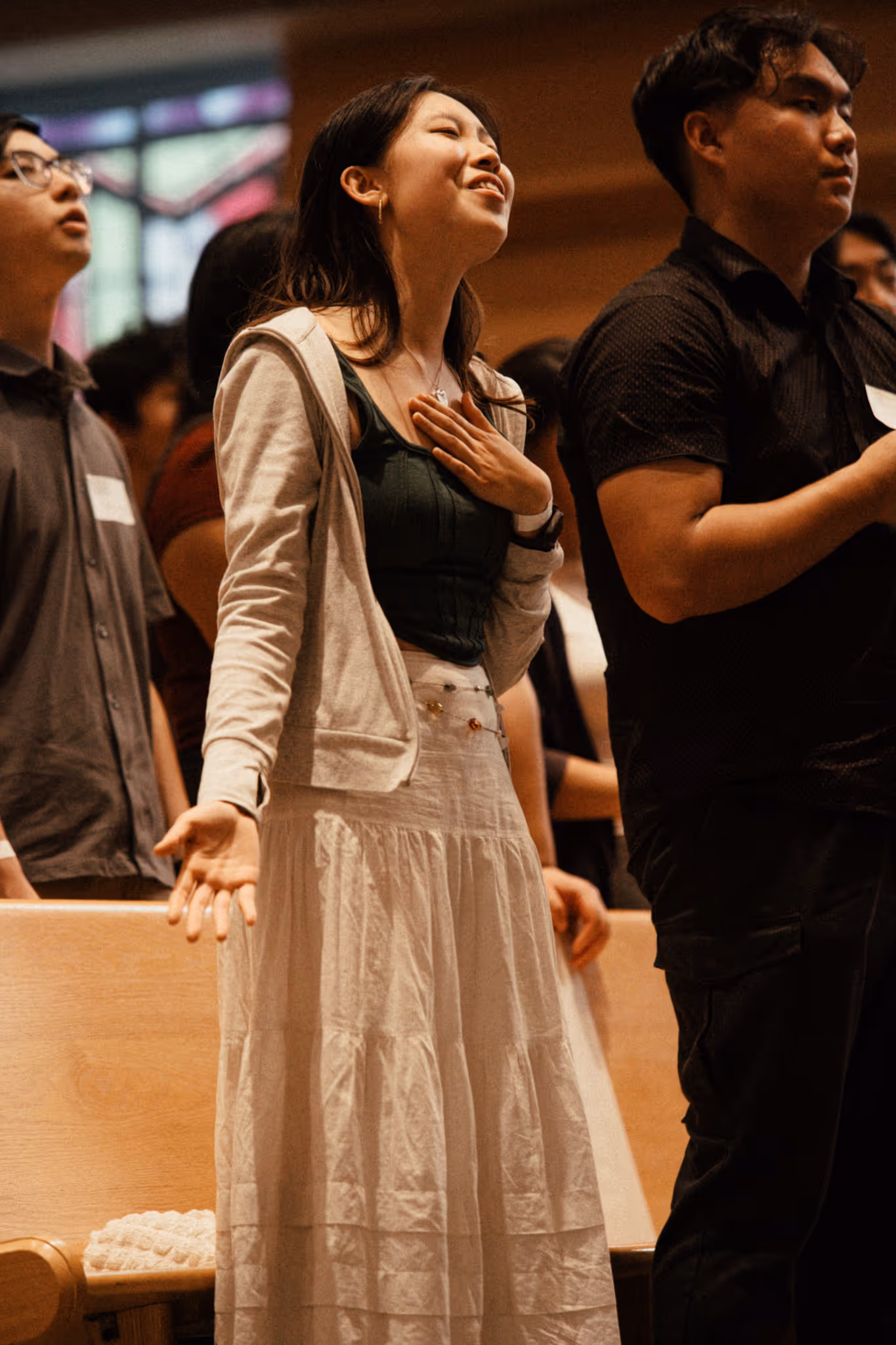 Young woman with hand on heart in prayer or worship at an AFC ministry gathering