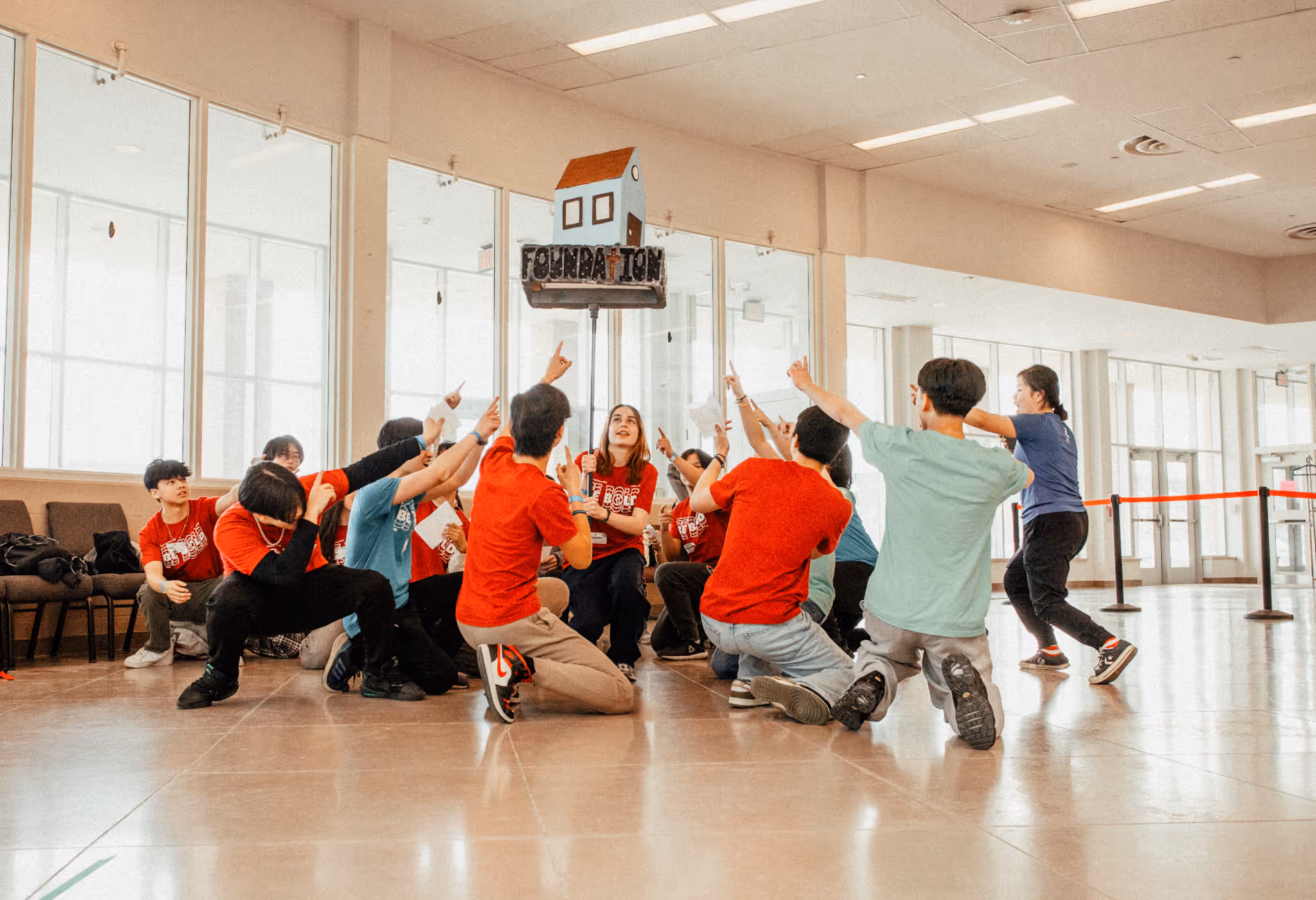 AFC high school students doing a team activity, pointing to a model house labeled 'Foundation'