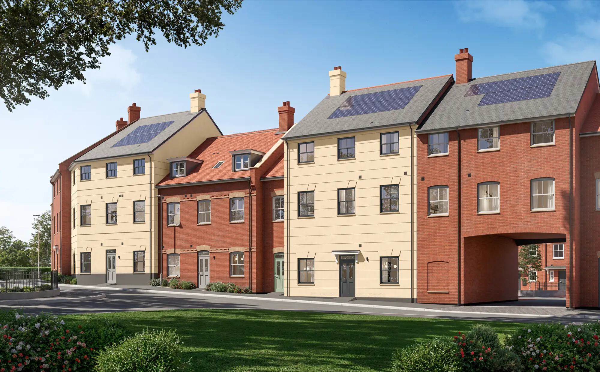 Block B at Hartstone: a row of modern, three-storey Hartstone apartment buildings with red brick and beige facades, featuring solar panels on the roofs, under a clear blue sky, and surrounded by greenery and a well-kept lawn.