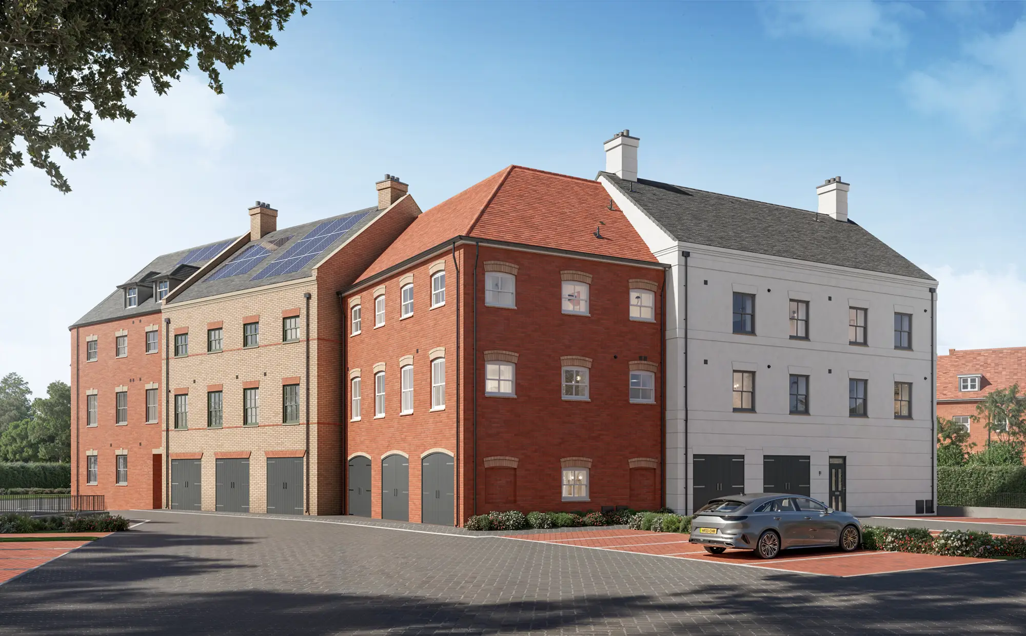 Block C at Hartstone: three modern, Hartstone multi-storey townhouses with red and white brick exteriors, solar panels on the roof, garages, and a parked car in front, under a clear blue sky.