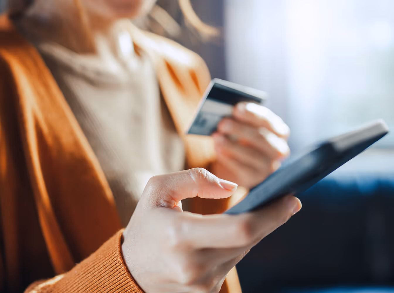 Person holding a credit card and using a smartphone for an online transaction.