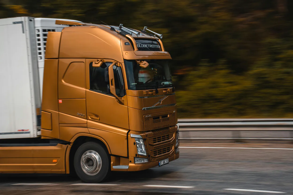Orange Volvo Globetrotter semi-truck driving on a highway with blurred background.