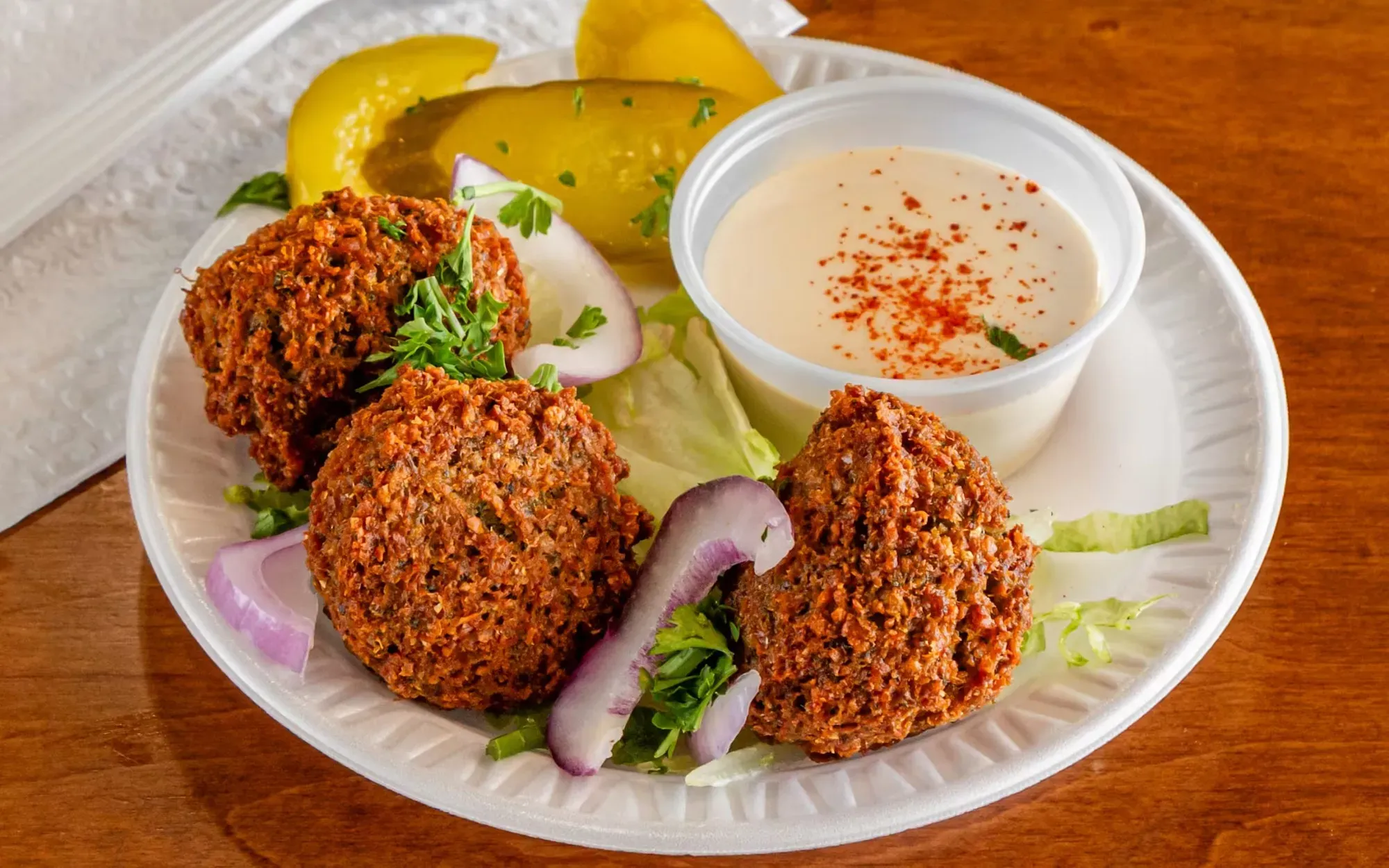 A plate featuring two beef patties accompanied by a side of pickles.