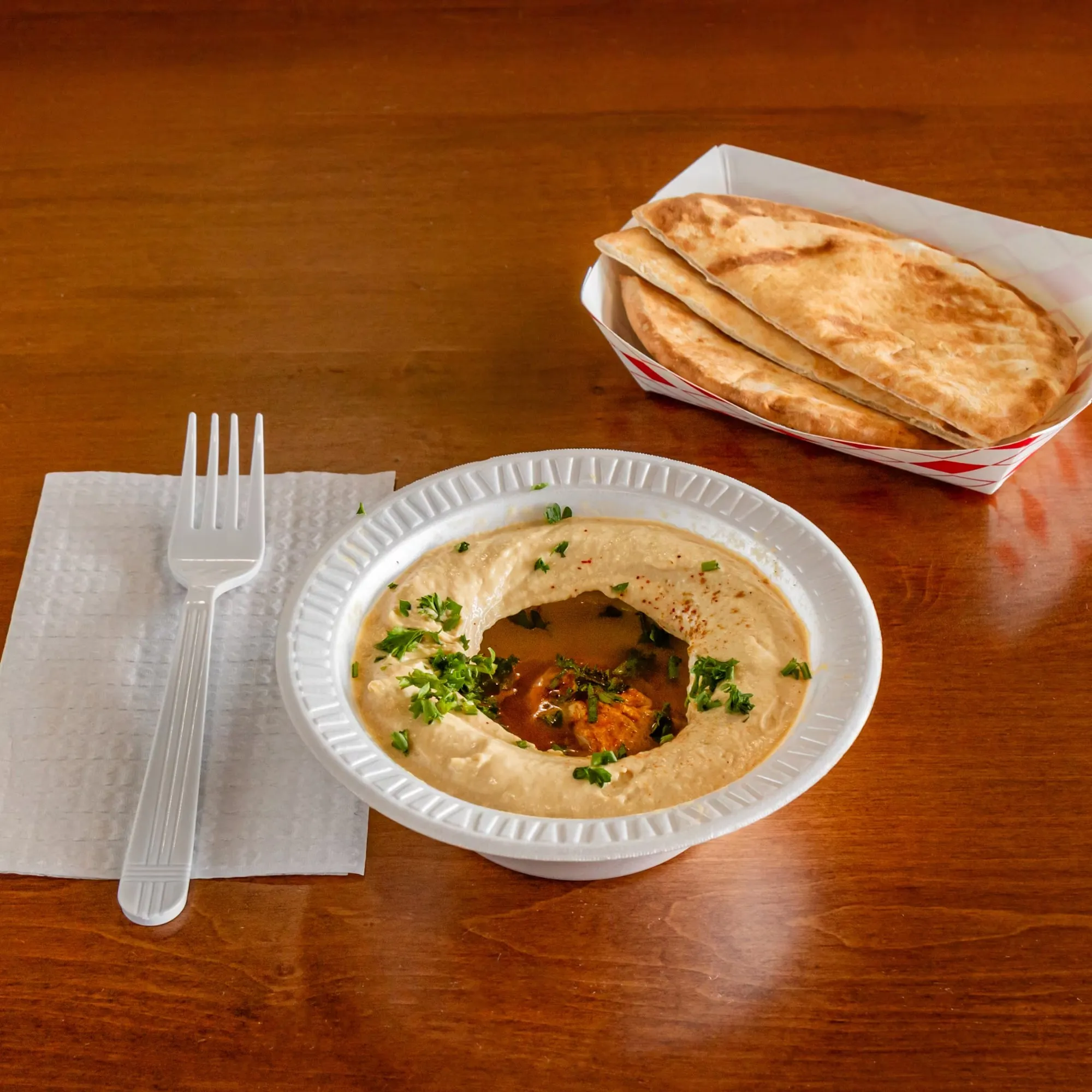A white bowl of food with a fork and spoon on a table.