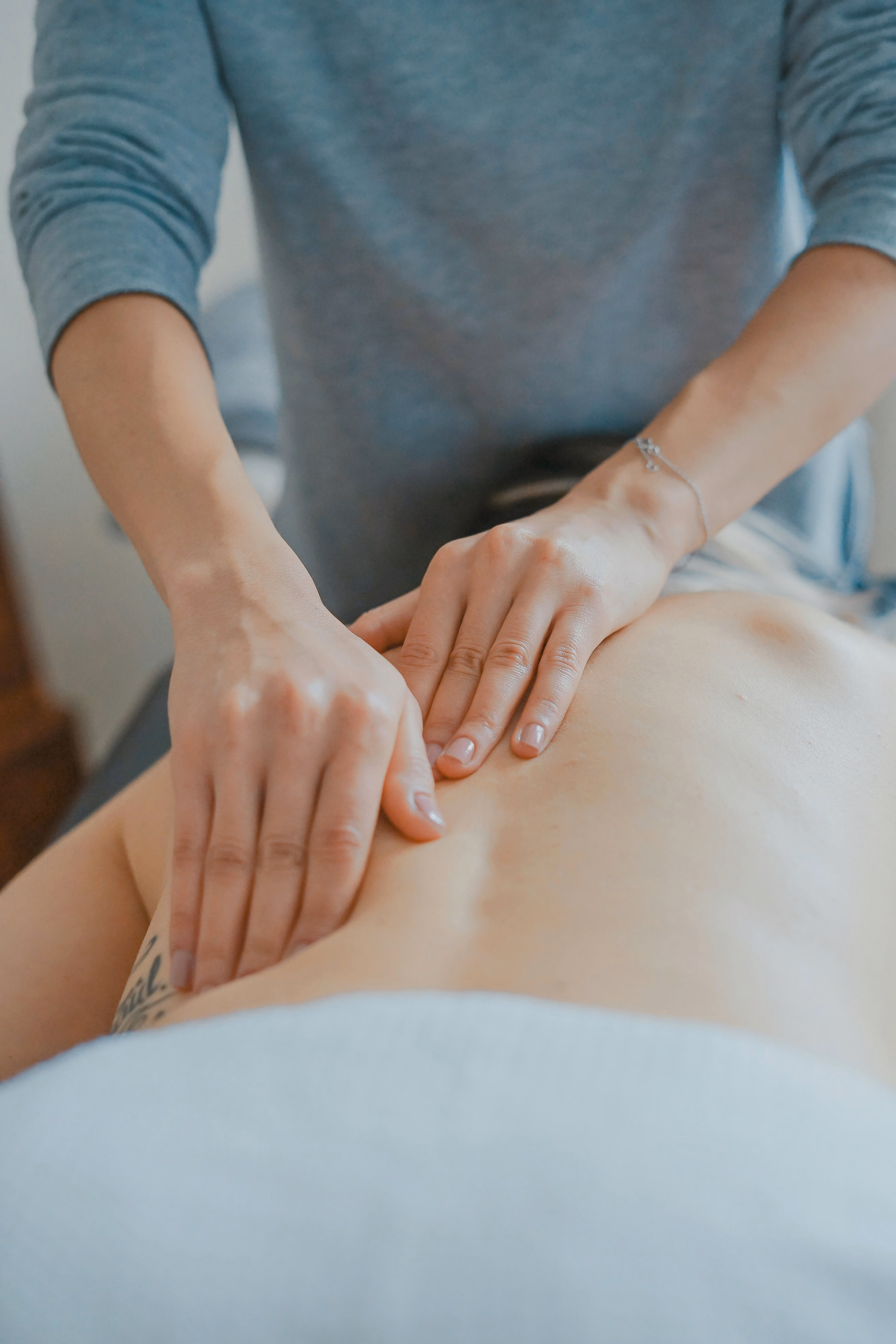 Close-up of a person receiving a back massage with hands applying pressure on bare skin.
