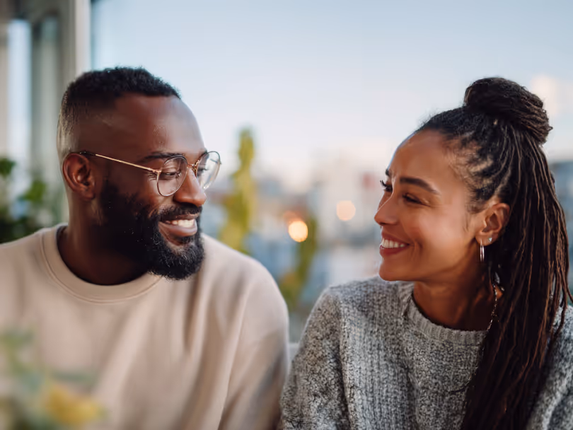 Smiling man with glasses and beard looking at smiling woman with long braided hair.