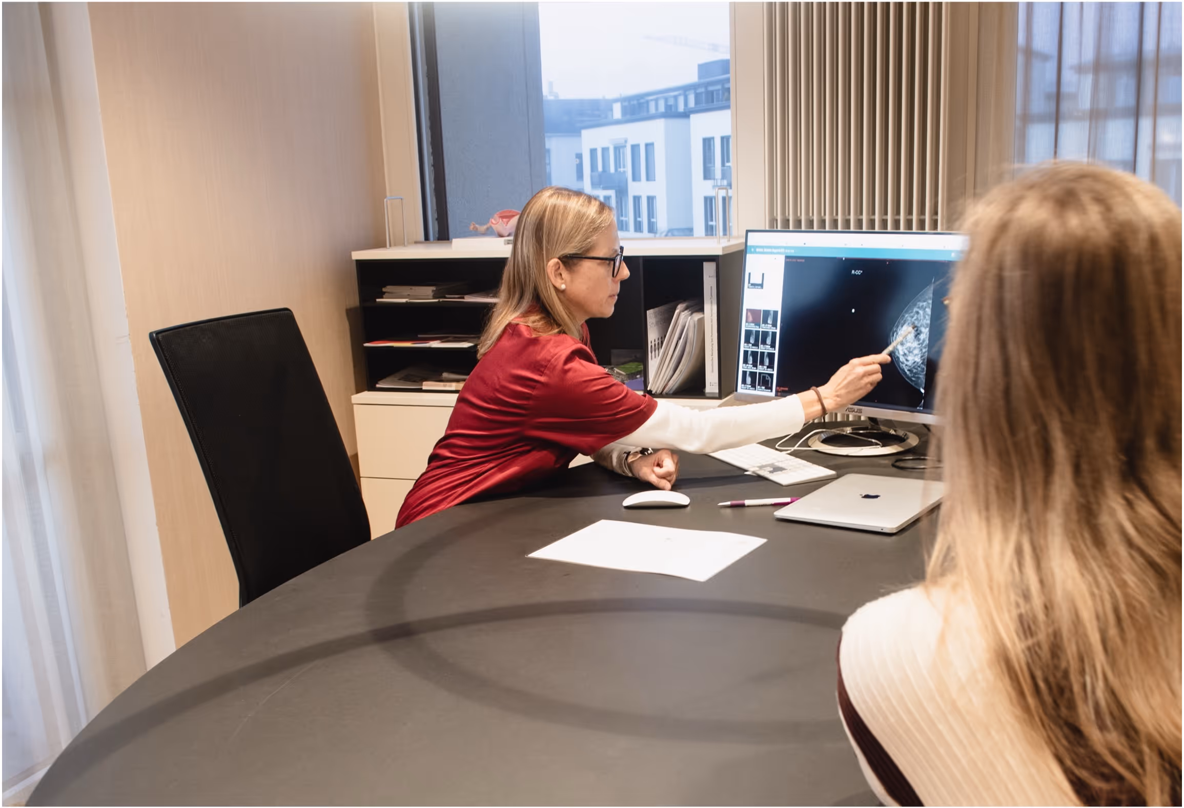 Ärztin zeigt einer Patientin am Computerbildschirm eine Mammographie-Aufnahme.