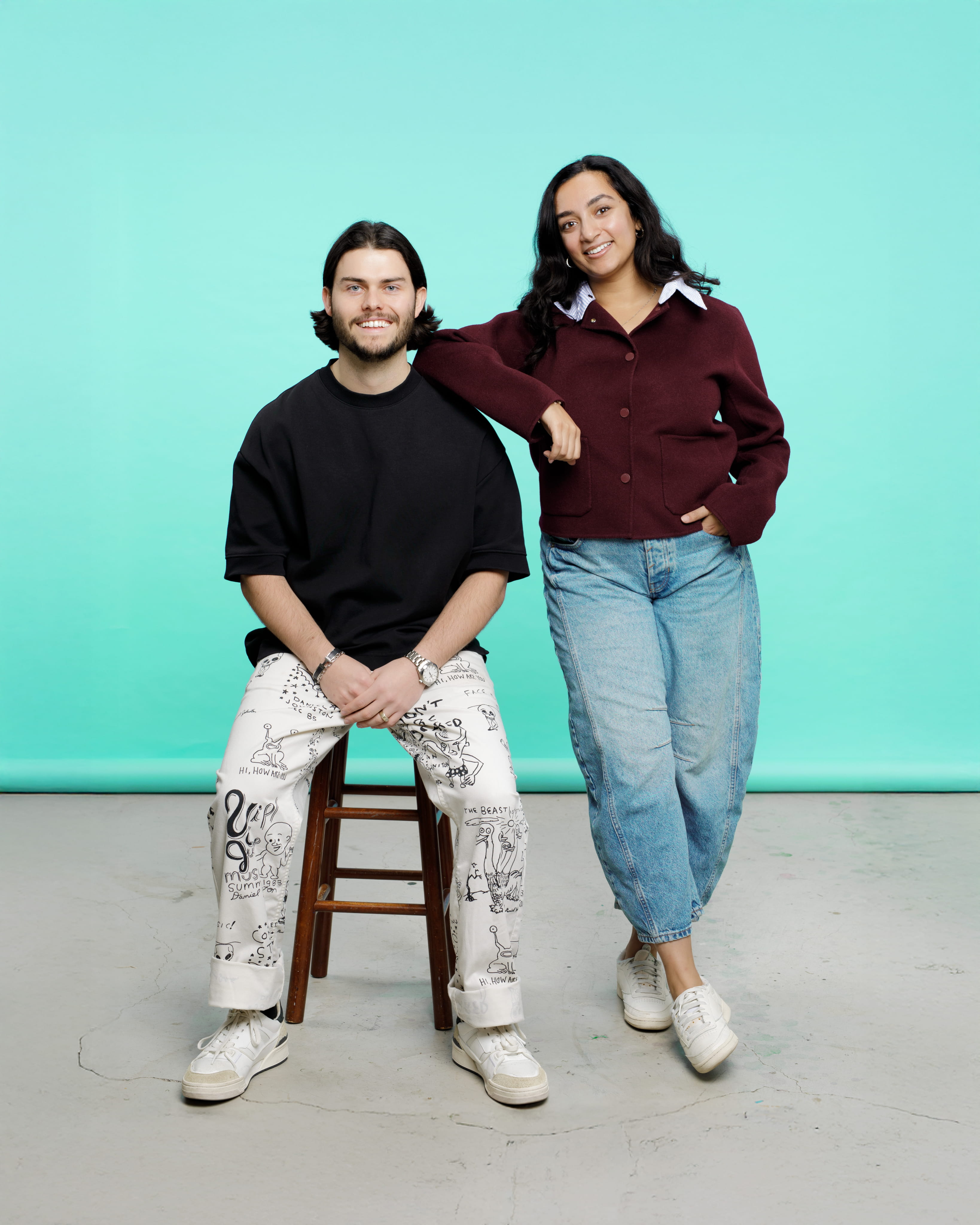 Image of the two co-founders, Tara and Alex. Alex is seated on a stool with Tara resting her arm on his shoulder.