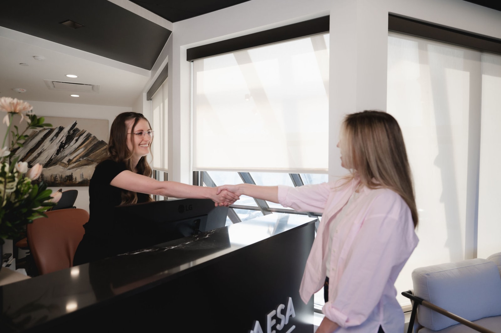 Female dental professional at front desk greeting and welcoming patient for appointment