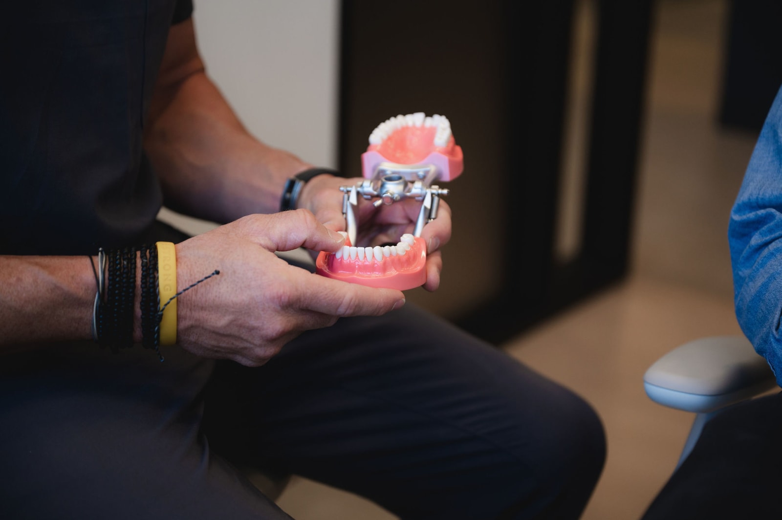Dentist holding dental model showing tooth implant to patient
