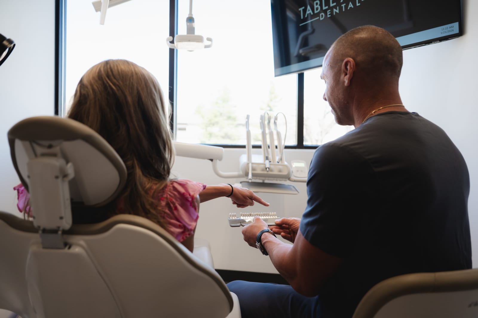 Dentist explaining retainer procedure to patient in treatment chair