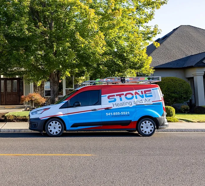 Parked Stone Heating and Air service van with ladder on rooftop in residential neighborhood.