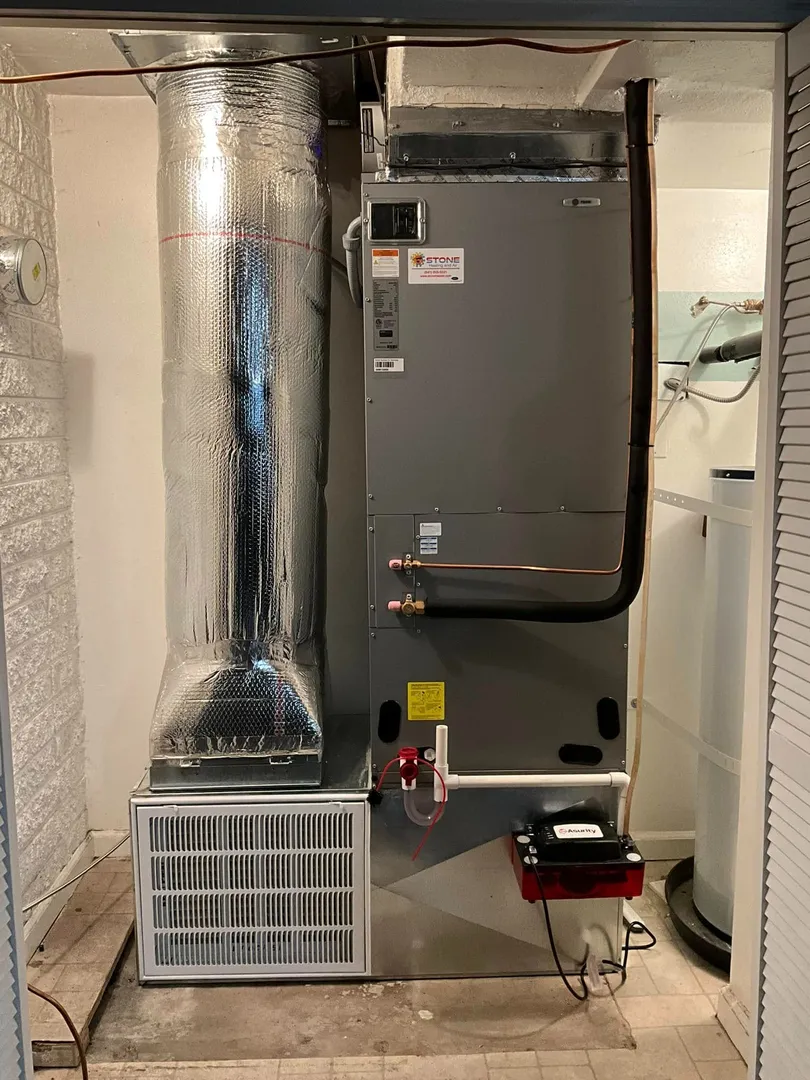 Indoor HVAC unit with insulated ductwork installed against a wall in a utility room.