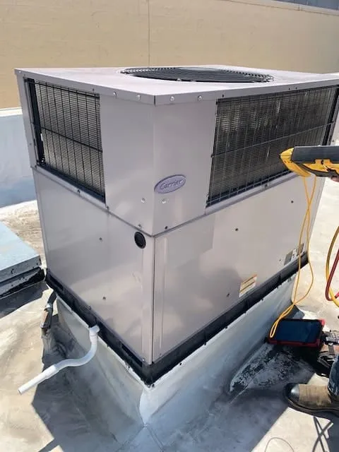 Rooftop HVAC unit with a Carrier logo, connected to diagnostic equipment with wires.