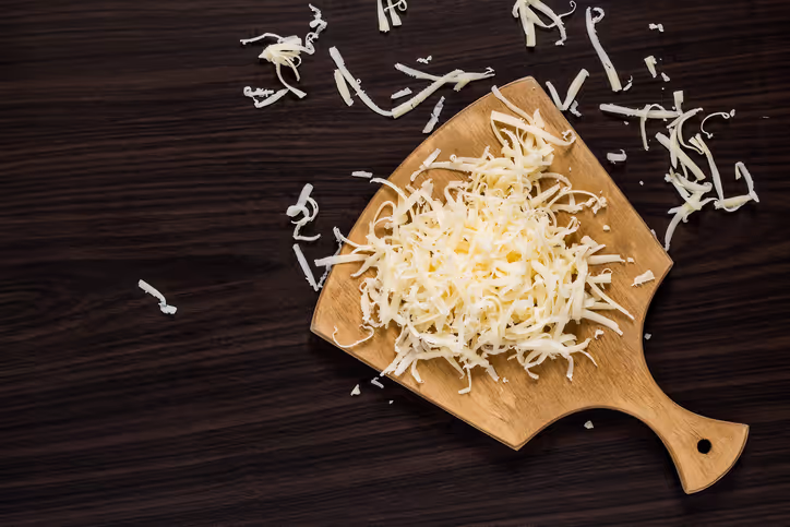 Shredded mozzarella cheese being served with tongs
