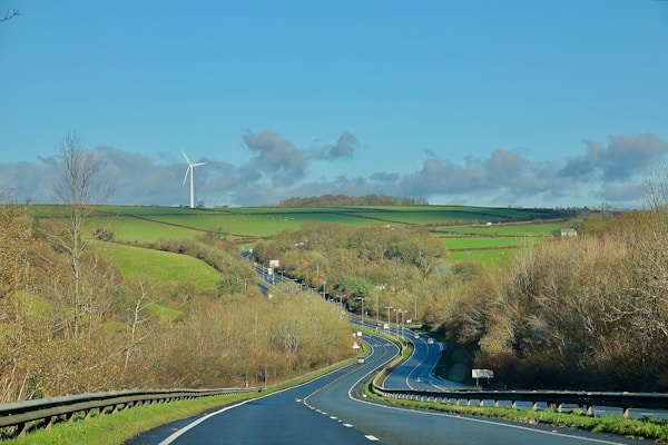 A winding road through green hills with a windmill.