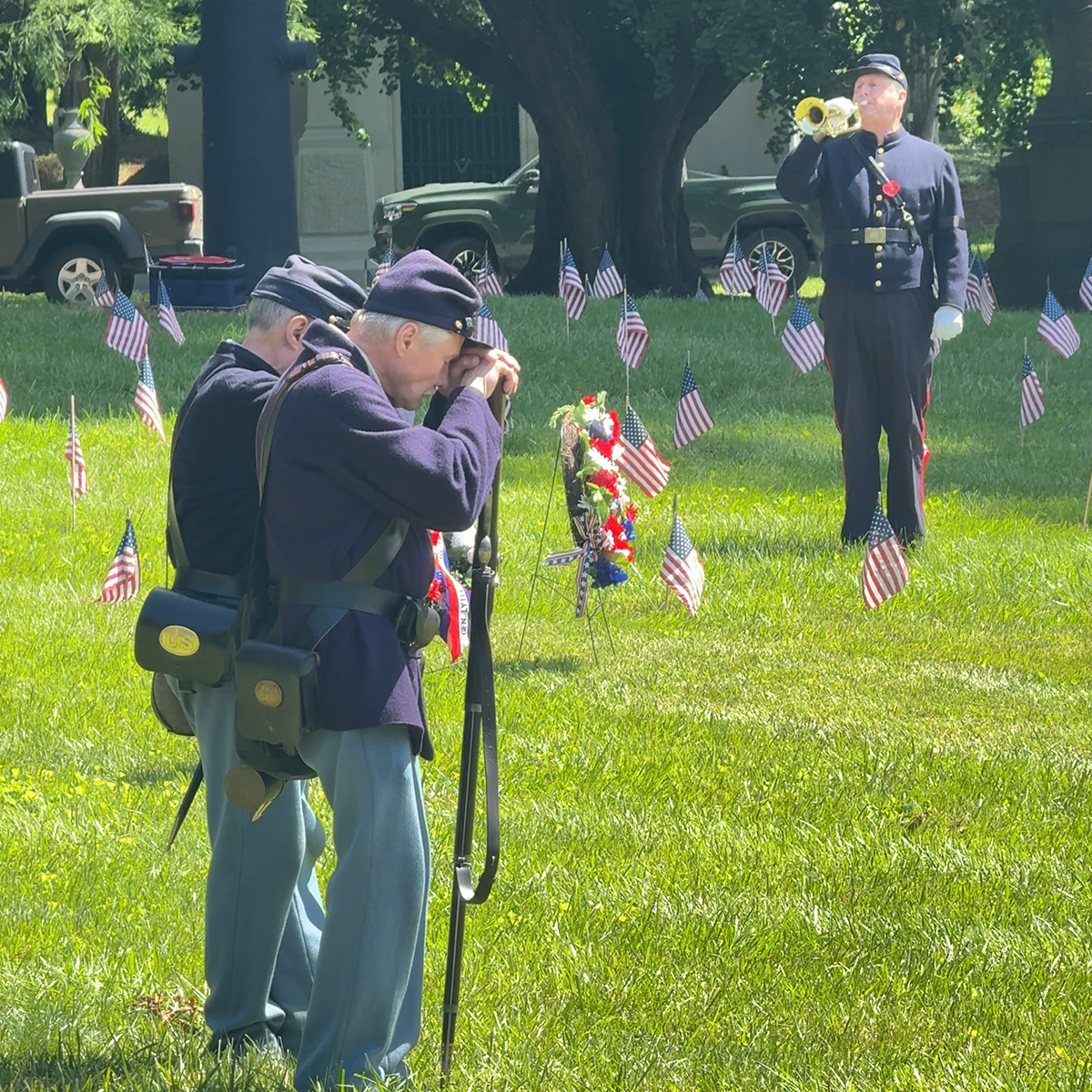 Two older men in Union uniforms, and a man playing a bugle during a Memorial Day services in 2025