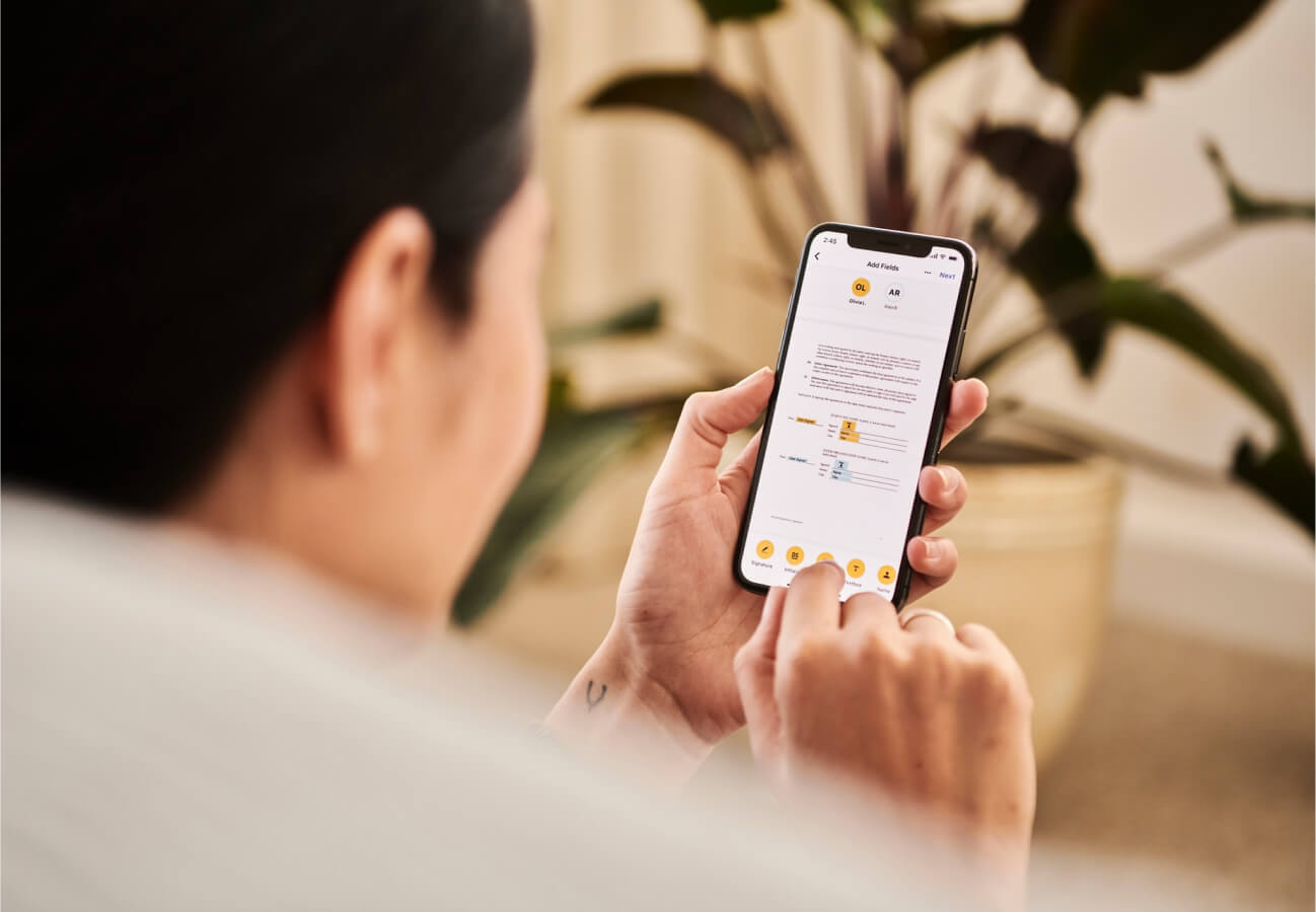 Person using a smartphone app to add fields and edit a digital document with text and highlighted sections.